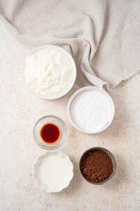 Bowls of cottage cheese, powdered allulose, vanilla extract, heavy cream, and cocoa powder.