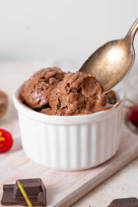 Chocolate cottage cheese ice cream in a ramekin being scooped with a spoon.