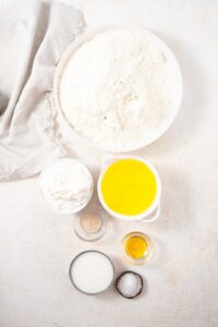 Bowls of bread flour, active dry yeast, cottage cheese, egg whites, honey, whole milk, and salt.