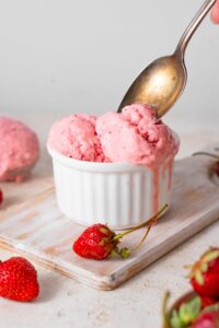 Scooping strawberry cottage cheese ice cream from a ramekin.