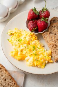Cottage cheese omelet garnished with chives, plated with fresh strawberries and whole wheat toast.