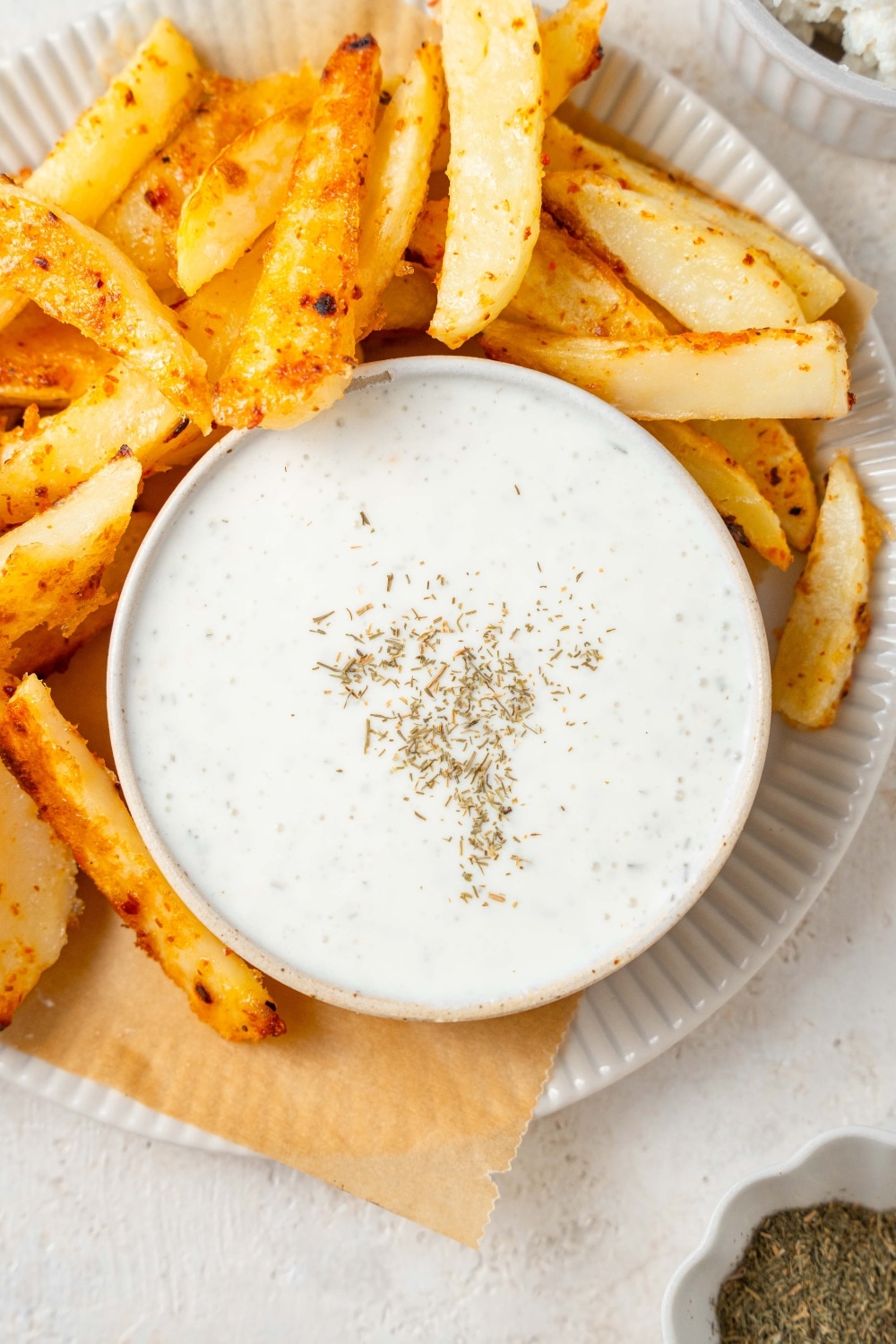 Cottage cheese ranch dip served in a bowl with a plate of seasoned french fries.