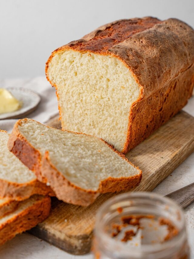 A sliced loaf of cottage cheese bread on a wooden cutting board.