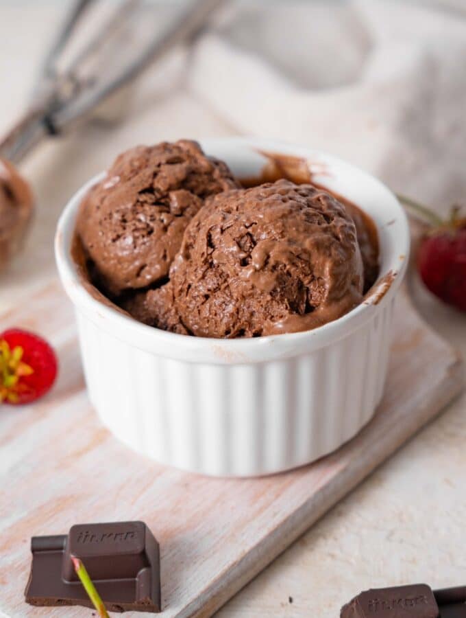 Chocolate cottage cheese ice cream in a ramekin, surrounded by strawberries and chocolate bar bits.