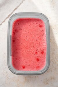Strawberry cottage cheese ice cream in a tub.