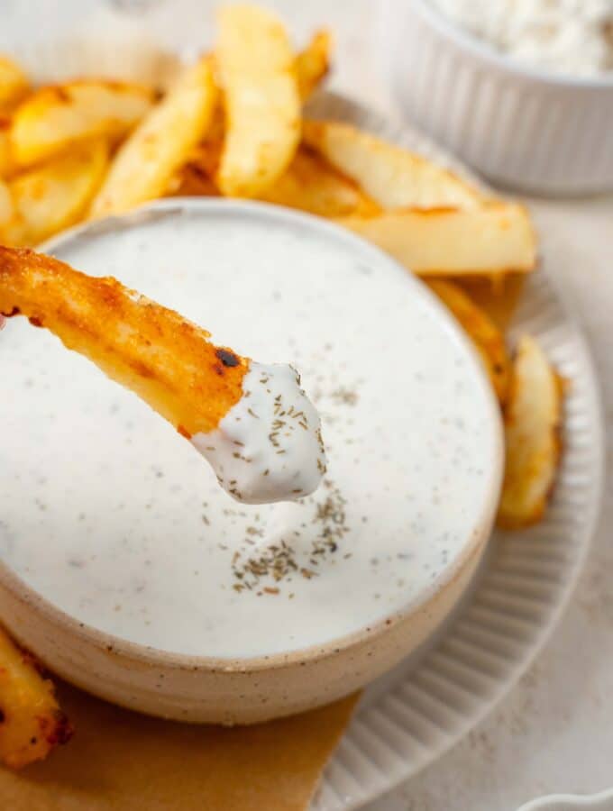 A seasoned french fry dipped into cottage cheese ranch dip.