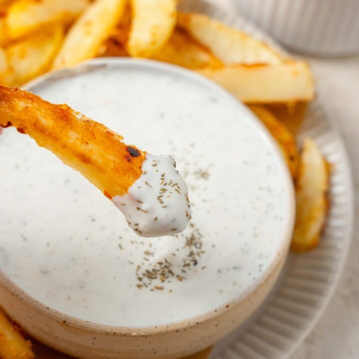 A seasoned french fry dipped into cottage cheese ranch dip.