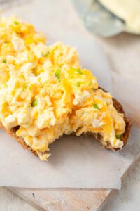 A closer look at cottage cheese omelet topped bread with a bite taken out.