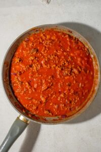 Ground beef and marinara sauce in a skillet.