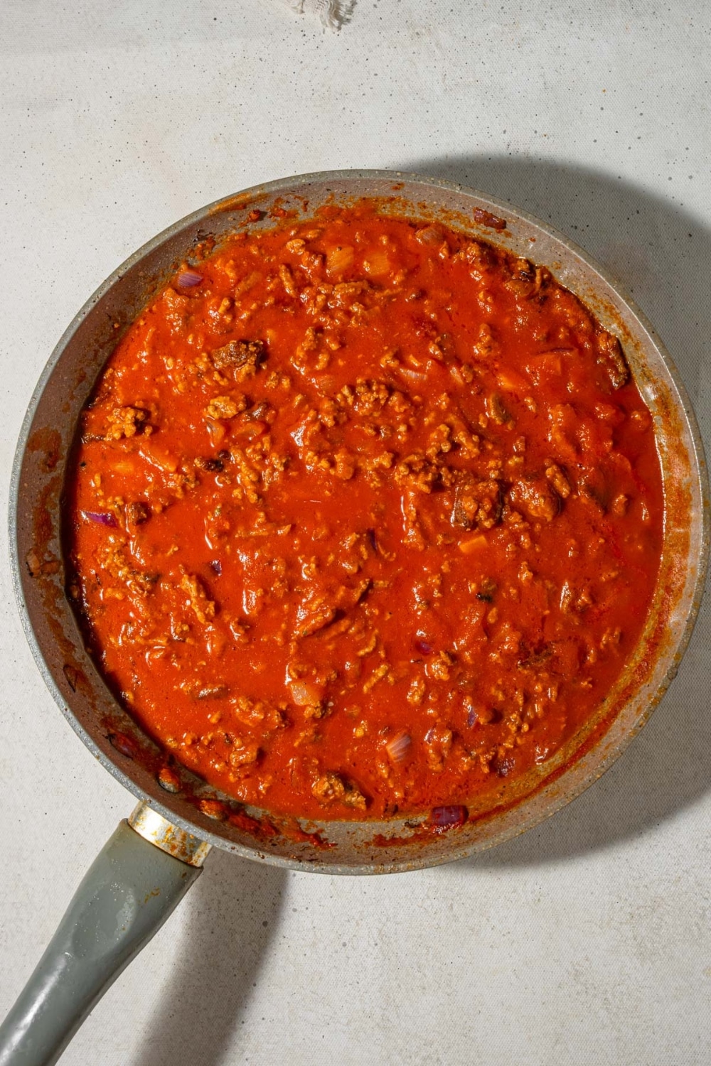 Ground beef and marinara sauce in a skillet.