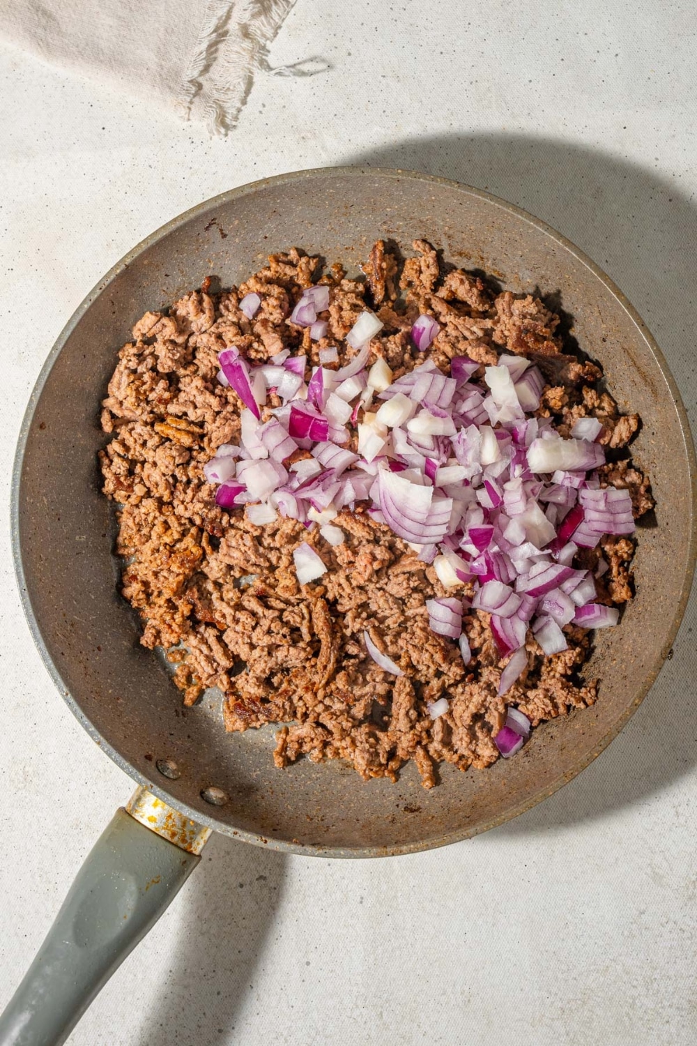 Chopped red onions and ground beef in a skillet.