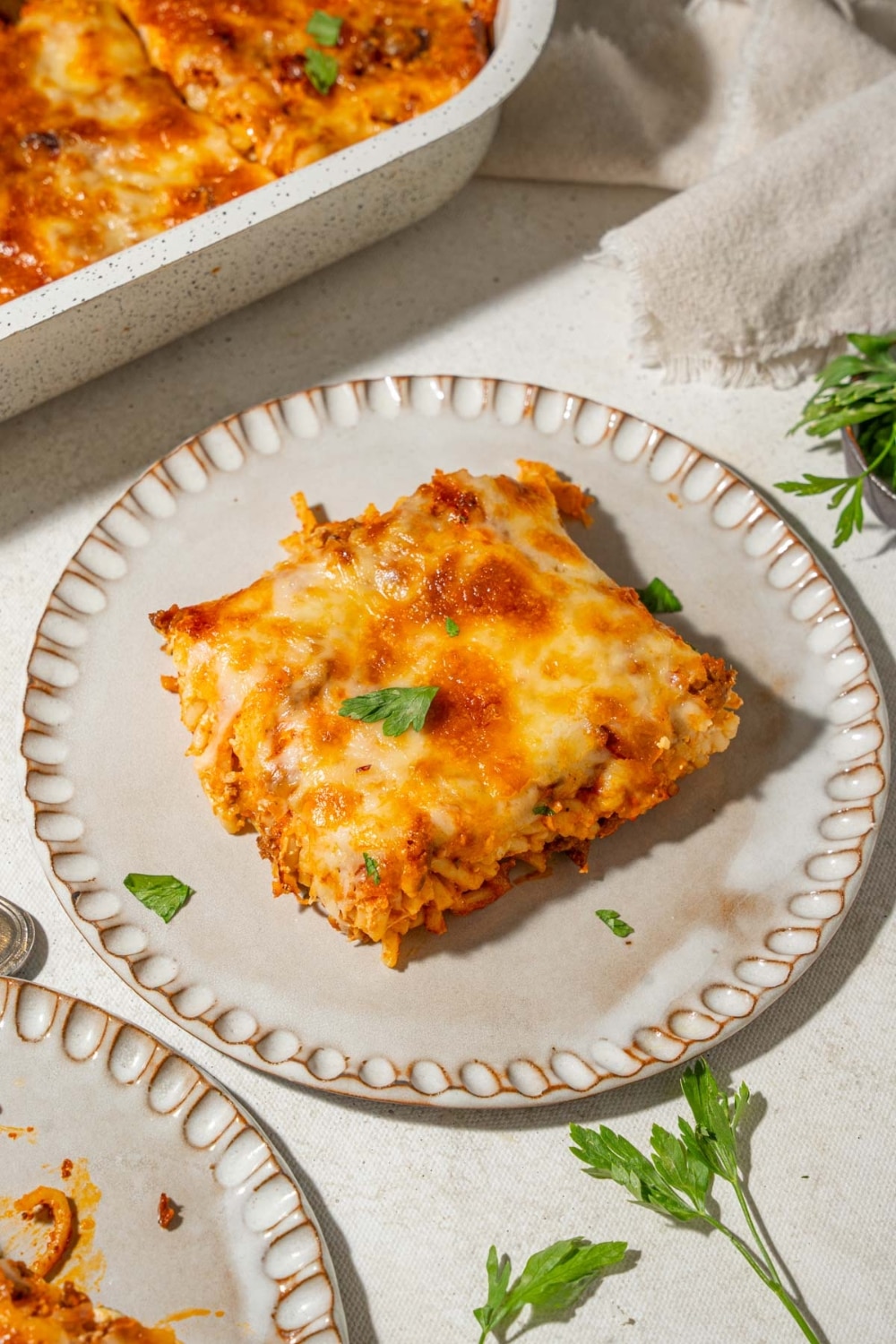 A slice of baked spaghetti garnished with herbs on a plate.