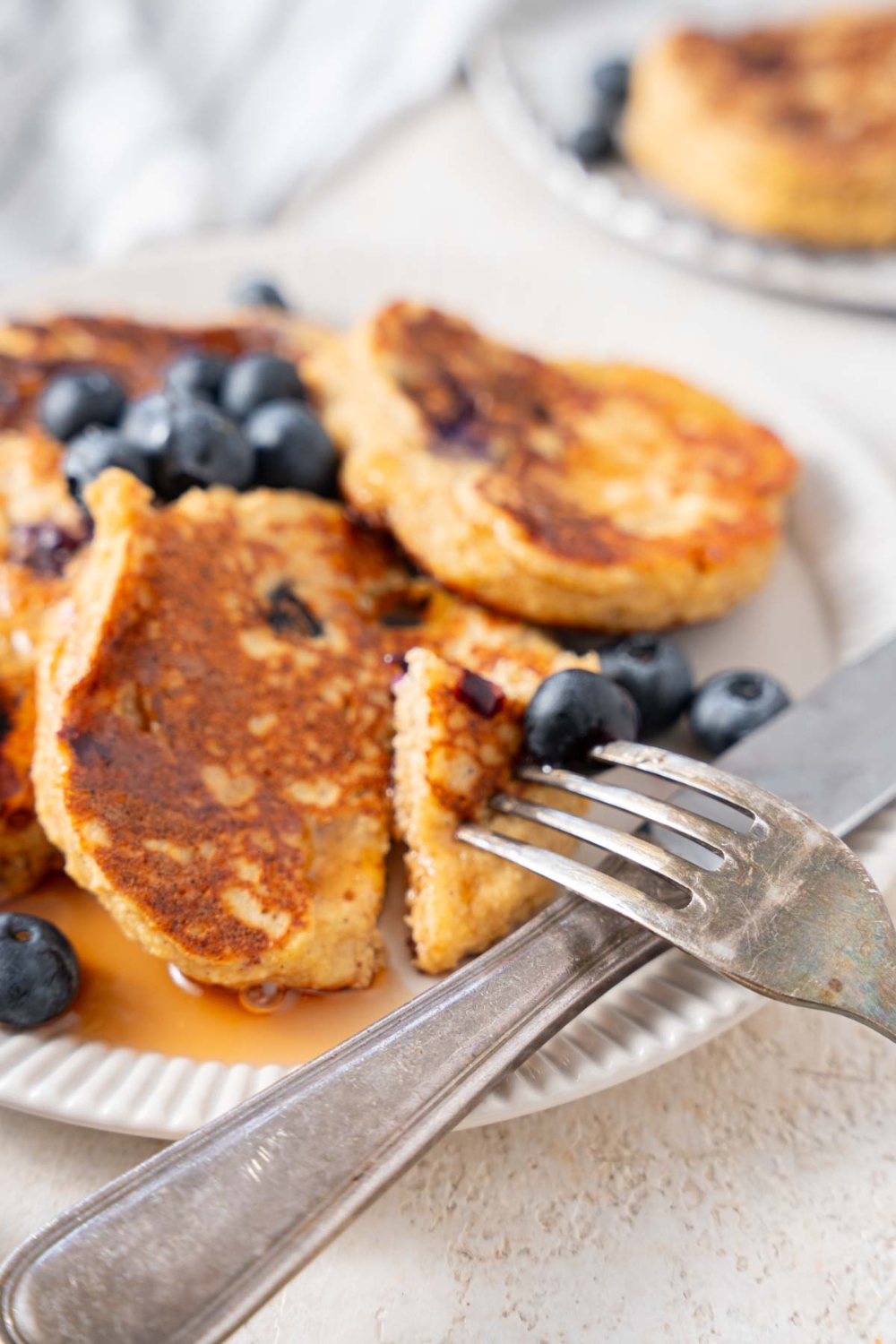 Cottage cheese banana blueberry pancakes being eaten with a fork and knife.