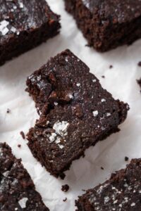 A closer look at one cottage cheese brownie garnished with flaky sea salt, with a bite taken out.