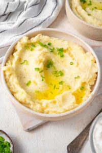 Cottage cheese mashed potatoes finished with chopped chives and melted butter in a bowl.