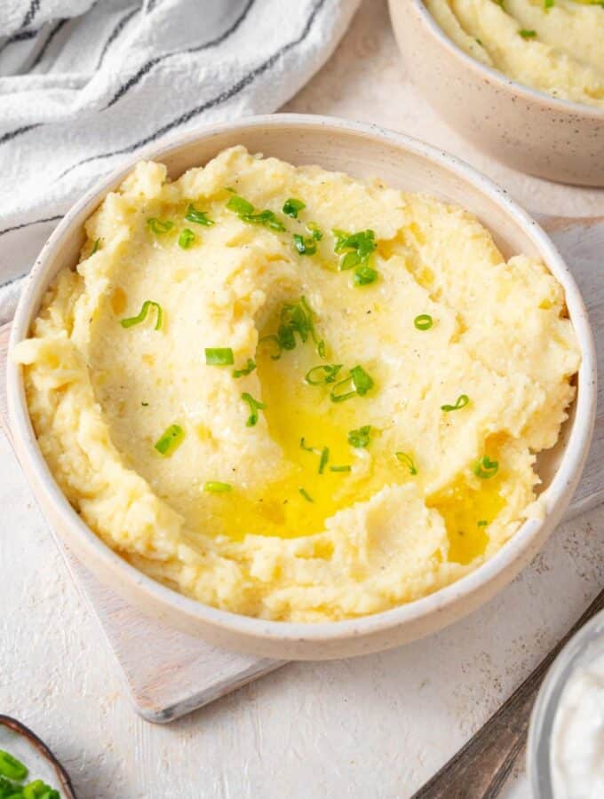 Cottage cheese mashed potatoes finished with chopped chives and melted butter in a bowl.