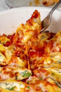 Lifting a spinach and cottage cheese stuffed shell with a fork.