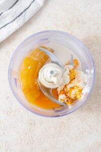 A banana, egg, cottage cheese, vanilla extract, almond milk, and maple syrup in a food processor.