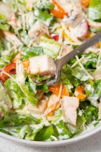 Scooping chicken Caesar salad with a fork.