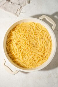 Cooked spaghetti in a white pot.