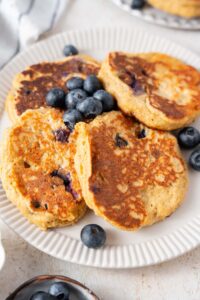 A closer look at cottage cheese banana blueberry pancakes on a plate with fresh blueberries.
