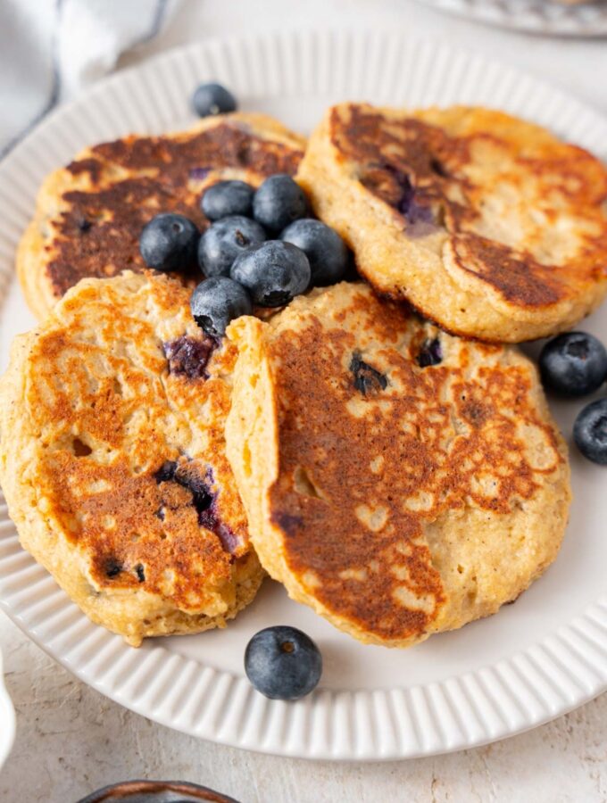A closer look at cottage cheese banana blueberry pancakes on a plate with fresh blueberries.