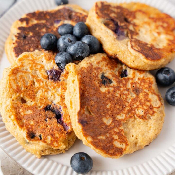 A closer look at cottage cheese banana blueberry pancakes on a plate with fresh blueberries.
