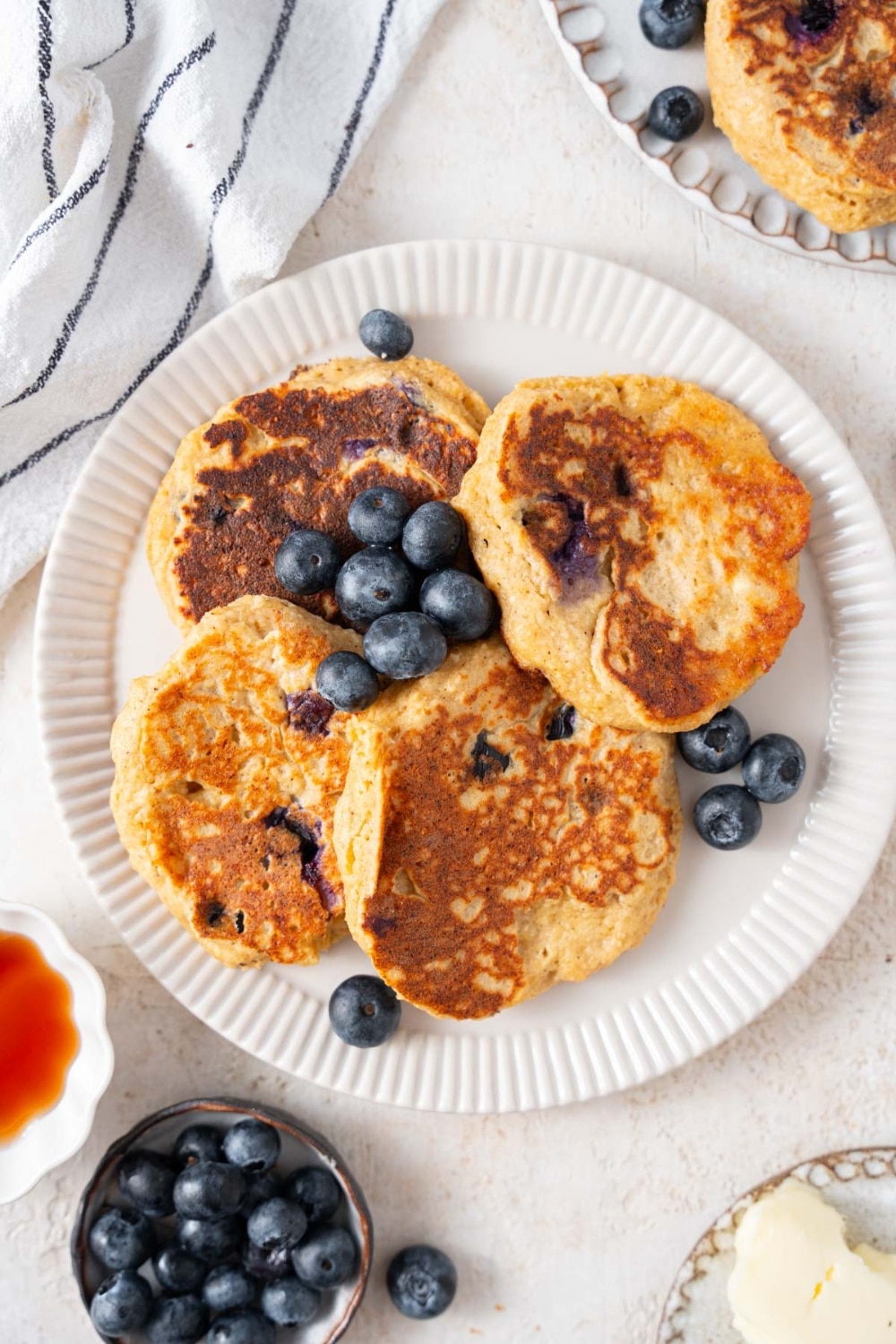 Top view of four cottage cheese banana blueberry pancakes garnished with fresh blueberries on a plate.