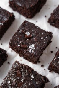 Cottage cheese brownies neatly arranged on a parchment paper and garnished with flaky sea salt.