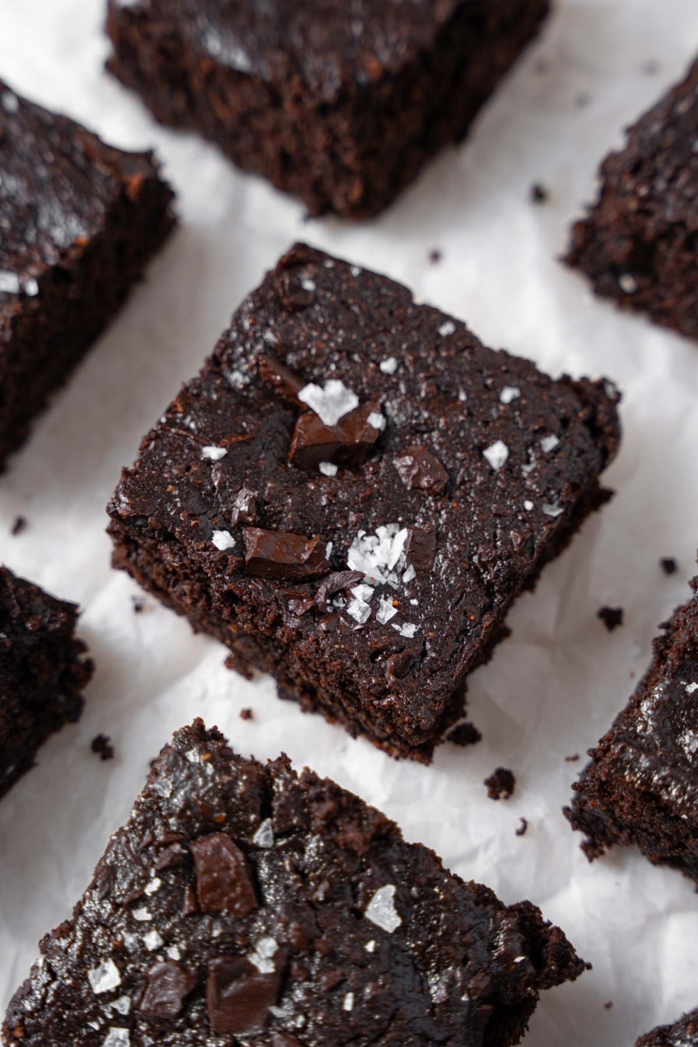 Cottage cheese brownies neatly arranged on a parchment paper and garnished with flaky sea salt.