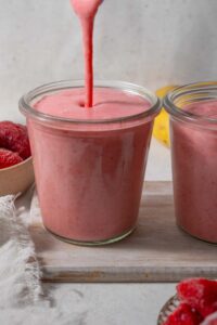 Strawberry cottage cheese smoothie being poured into a glass next to another smoothie.