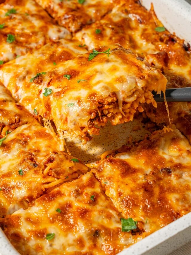 Lifting a slice of million dollar spaghetti from a casserole dish.