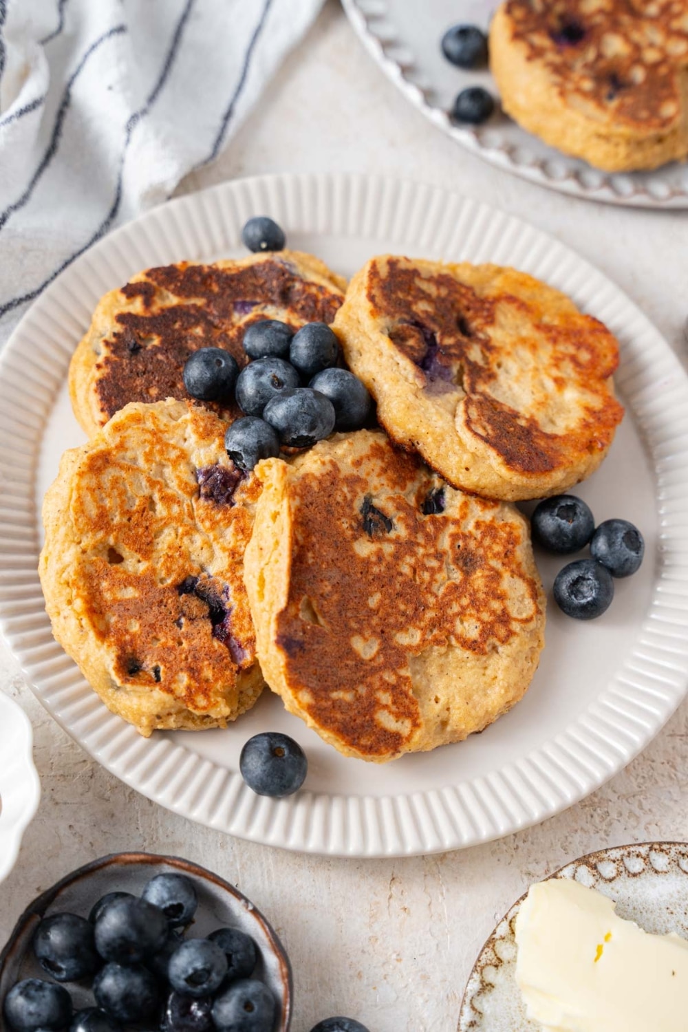 A plate of cottage cheese banana blueberry pancakes with fresh blueberries.