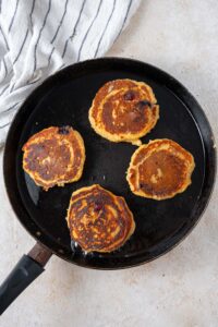 Four cottage cheese banana blueberry pancakes in a skillet.