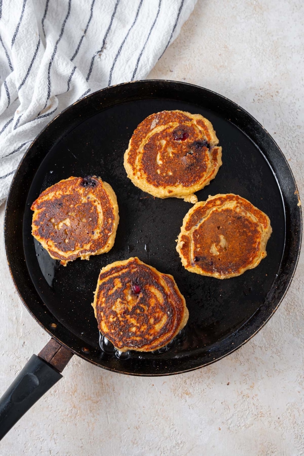 Four cottage cheese banana blueberry pancakes in a skillet.