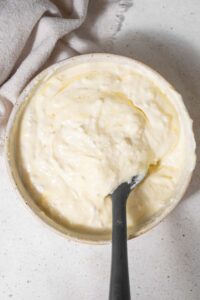 Cottage cheese, mozzarella, egg, and parmesan cheese mixed together in a bowl with a rubber spatula.