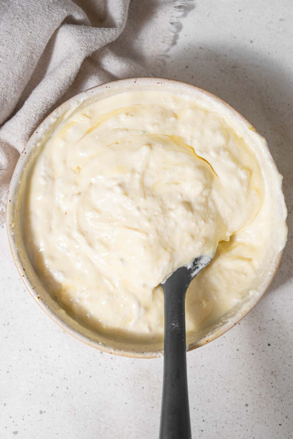 Cottage cheese, mozzarella, egg, and parmesan cheese mixed together in a bowl with a rubber spatula.