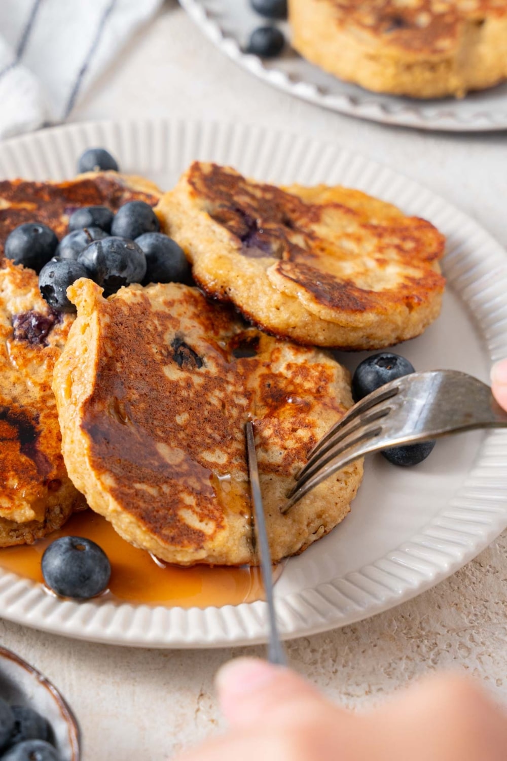 Cutting into cottage cheese banana blueberry pancakes with a fork and knife.