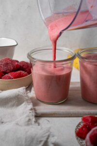 Pouring strawberry cottage cheese smoothie into a glass.