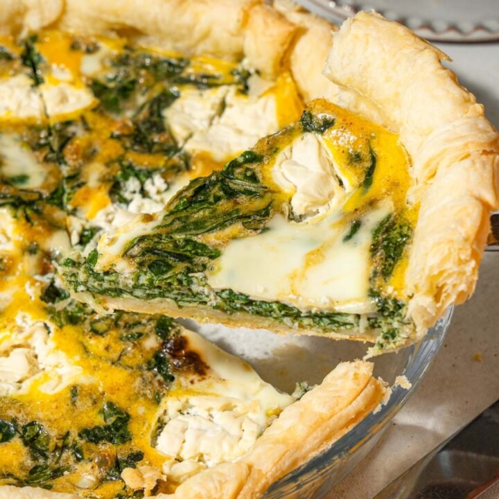 A slice of spinach cottage cheese quiche being lifted from a pie pan.