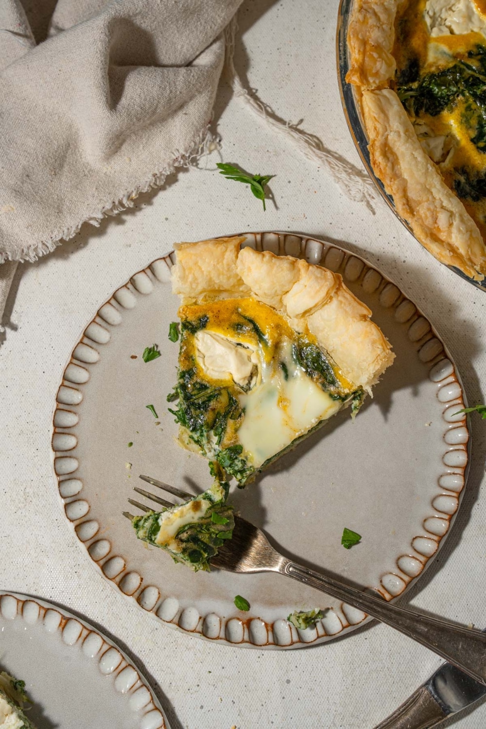 A slice of spinach cottage cheese quiche on a plate, cut with a fork.