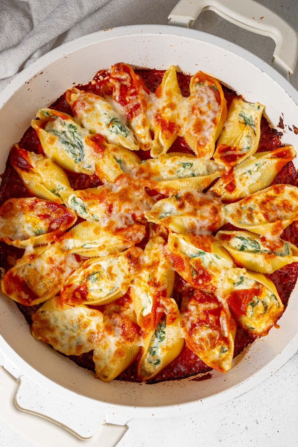 Top view of spinach cottage cheese stuffed pasta shells in cheesy marinara sauce.