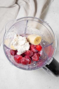 Cottage cheese, banana, frozen strawberries, and almond milk in a blender.